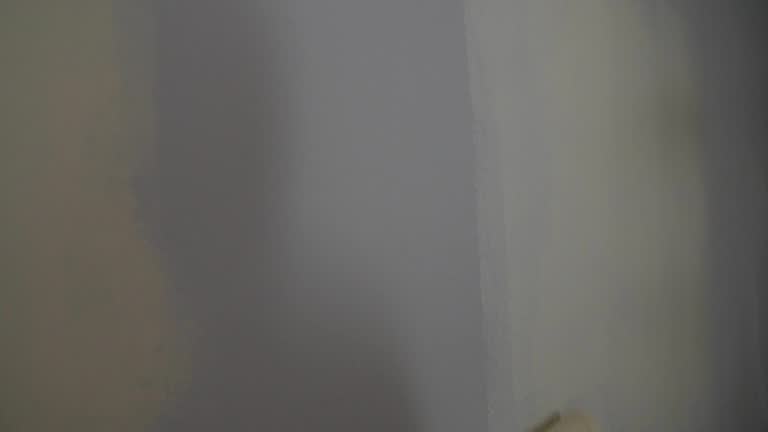 Painting out a bare wall with a paint roller with white paint