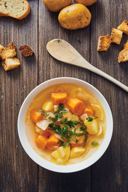 zuppa di verdure in ciotola bianca circondata dagradients su tavolo di legno - stuffing celery onion spoon foto e immagini stock