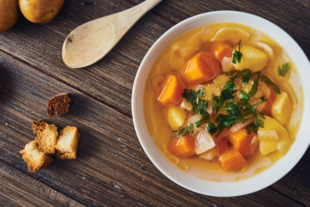 sopa de verduras en un tazón blanco sobre mesa de madera - stuffing celery onion spoon fotografías e imágenes de stock