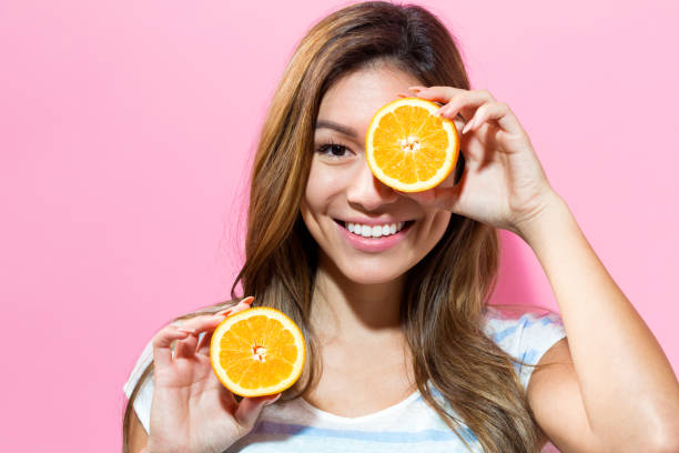 istock Happy young woman holding oranges halves 695641422