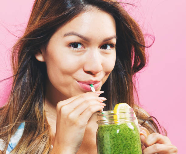 istock Happy young woman drinking smoothie 695641424
