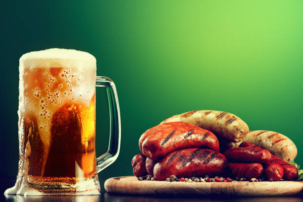 Mug of beer with grilled sausages on green background. Beer Fest drink and food stock photo