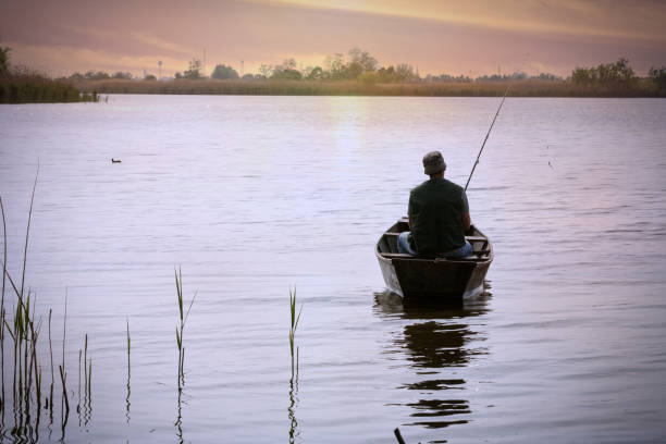 istock fishing-Fisherman on boat at sunset 695642010