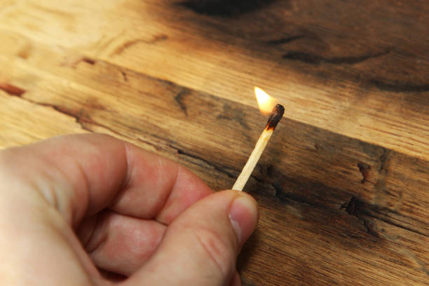 istock A Caucasian hand holding a lit match. This image also contains a wooden background and can be used to represent fire starting or arson. 695644278