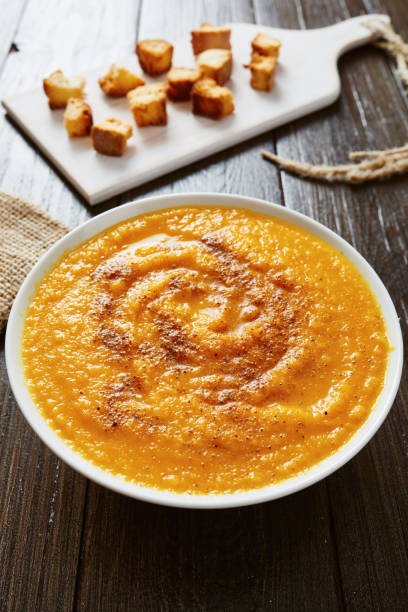 istock Pumpkin soup in white bowl with bread crouton on wood table 695644388