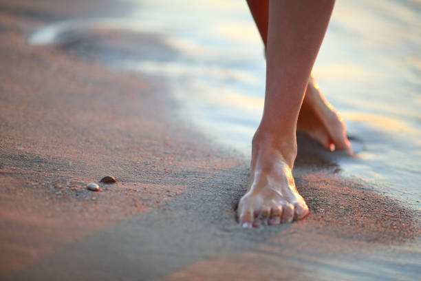 istock Woman walking on the beach at sunset 695649222
