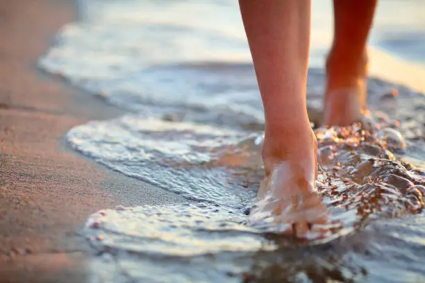 Photo of Female feet step on the sea wave