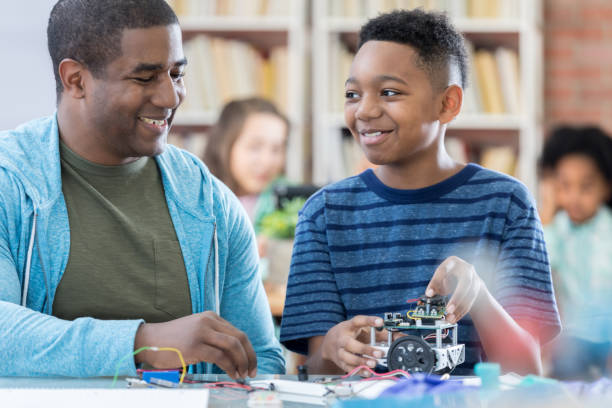 istock Male mentor and junior high student discussing robotics project and laughing 695655874