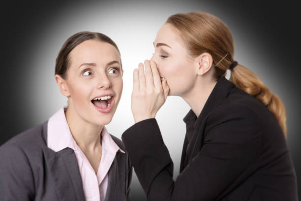 istock coworkers sharing a secret 695660376