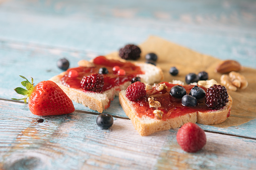 Close-up of toast with homemade strawberry jam on table with berry fruits and nuts