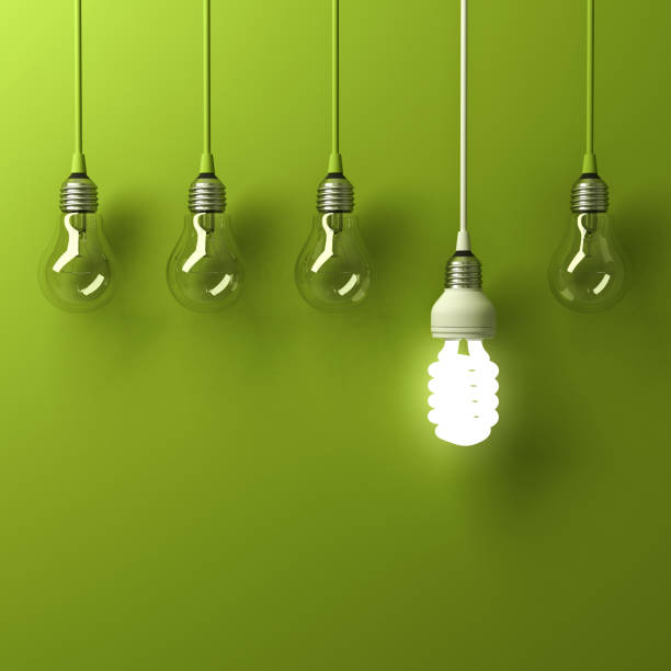 One hanging energy saving light bulb glowing different standing out from unlit incandescent bulbs with reflection on green background, leadership and different creative idea concept One hanging energy saving light bulb glowing different standing out from unlit incandescent bulbs with reflection on green background, leadership and different creative idea concept. 3D rendering. energy efficient lightbulb stock pictures, royalty-free photos & images