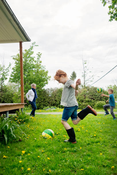istock Kids playing ball outdoors around house in springtime. 695667632
