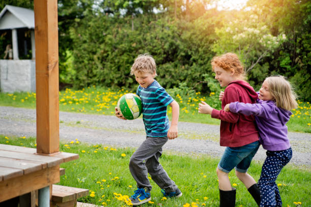 istock Kids playing ball outdoors around house in springtime. 695667968