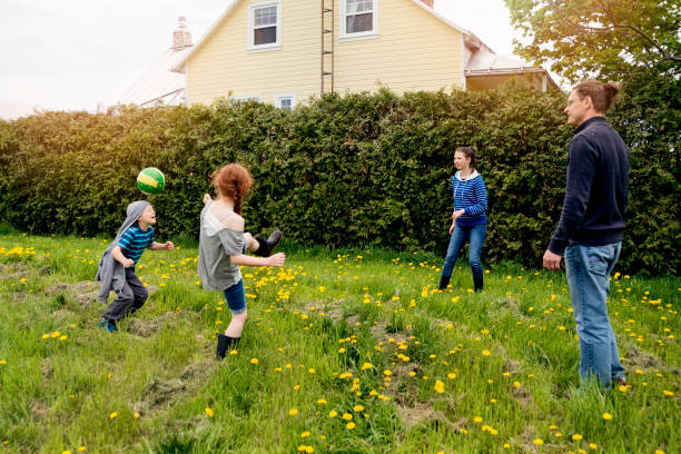 istock Kids playing ball outdoors with dad around house. 695670284