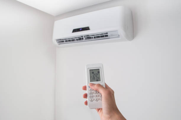 istock Hand holding remote control for air conditioner on white wall. 695678316