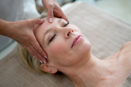 Portrait of an adult woman getting a face massage at the spa - beauty treatment concepts