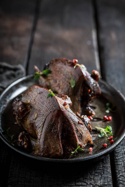 istock Two roasted pigeons with spices and pepper on dark background 695689972