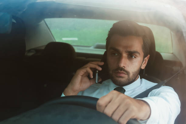 istock Young businessman talking with his mobile phone inside car while driving 695690080