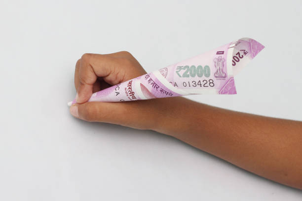 istock Child's hand hold 2000 rupee note just like a pen. 695698490