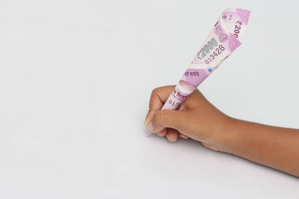 istock Child's hand hold 2000 rupee note just like a pen. 695698504