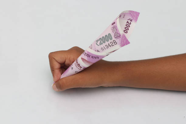 Child's hand hold 2000 rupee note just like a pen.