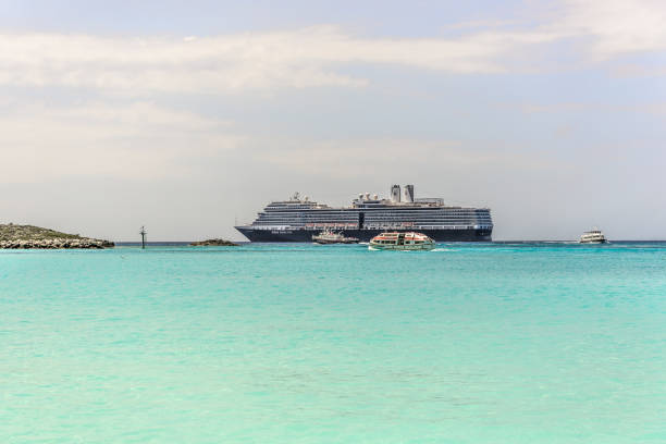 Arriving Half Moon Cay Little San Salvador Island, Bahamas - April 1, 2017: Holland America cruise ship arrived at company's private island - Half Moon Cay. Half Moon Cay is also known as Little San Salvador Island, is one of the islands that make up the arechipelago of the Bahamas. The island does not have deep water docking, requireing the use of tenders for cruise ship passengers to disembark and embark. cay stock pictures, royalty-free photos & images