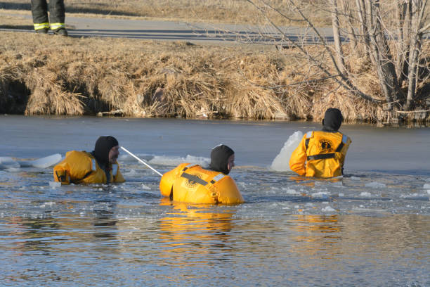 Arvada, Colorado attempt for dog rescue in winter ice covered lake Three Firefighters breaking ice at Lake Arbor in Arvada Colorado searching for dog arcada stock pictures, royalty-free photos & images