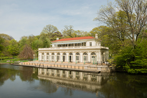 This is a horizontal, color photograph of the landmark Beaux Arts boathouse built in 1904 on the Lullwater of the Lake architecture in Brooklyn's Prospect Park in New York City.