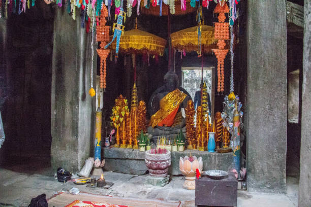 At the western entrance of Angkor Wat  stands this 5 meters tall statue of  Vishnu, known locally as Ta Reach, revered by Hindus and Buddhists alike for its representation of the “King of the ancestors and spirits”. It is carved from a single piece of  sandstone and is draped with colorful clothing and  offerings from pilgrims visiting the site.