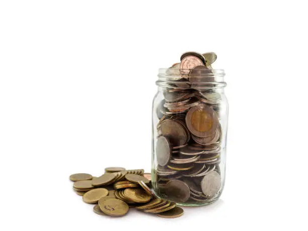 Photo of Many coins for saving in glass jar on white background