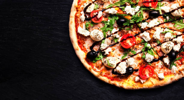 istock Pizza with mozzarella, 4 cheese, olives, leaves, goat cheese and balsamic sauce  top view with copy space for restaurant menu on black background. 695744040