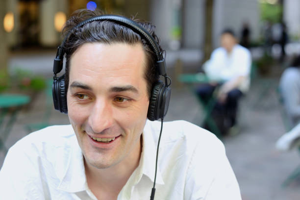 istock Man sitting outside with headphones on 695744882