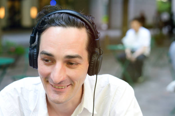istock Man sitting outside with headphones on 695744892