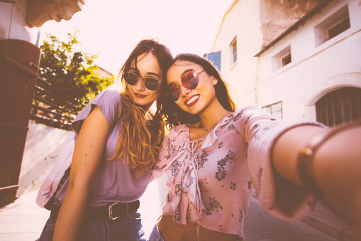 Hipster women on holidays in Spain taking a selfie on their smartphone in old streets