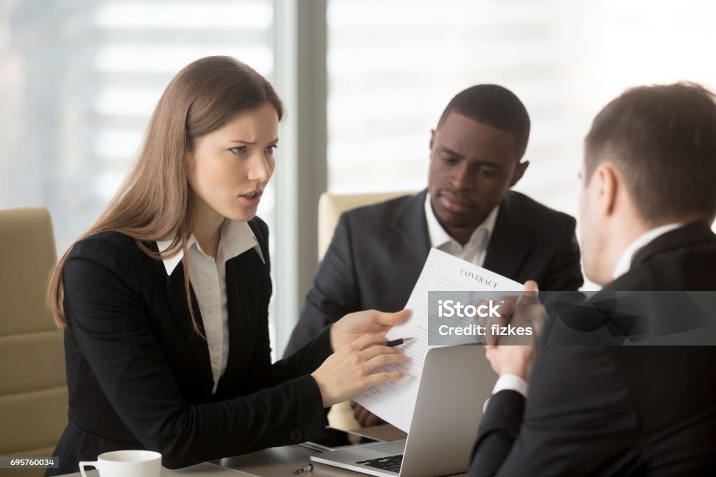 Angry dissatisfied businesswoman arguing with contractor, pointing at contract Angry dissatisfied businesswoman holding contract arguing with contractor, pointing at terms failed to perform, demanding termination, loss compensation, defrauded cheated investor protecting rights Lawyer Stock Photo