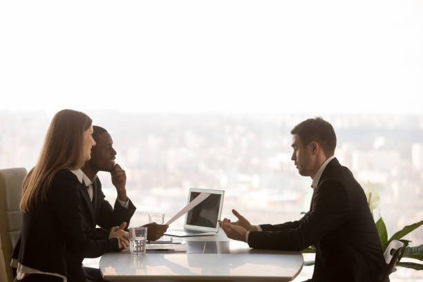 Male applicant and multi-ethnic recruiters during job interview, side view