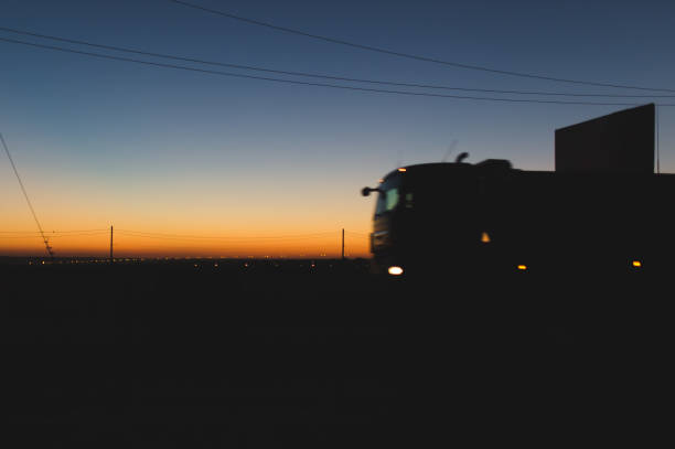 istock Speeding oncoming trucks with glowing lights on the highway after sunset 695795708