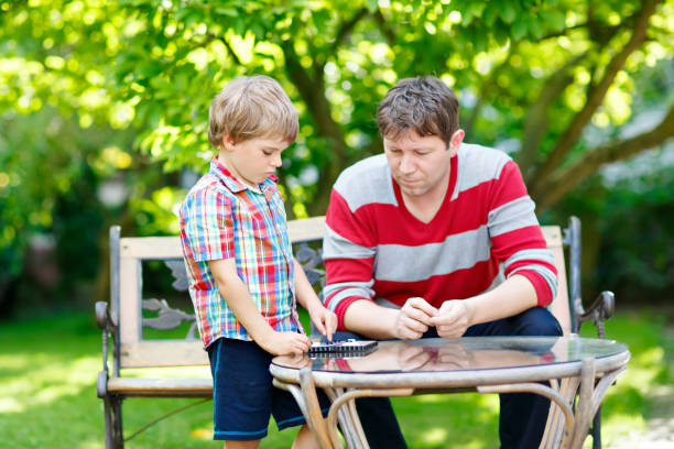 istock Little kid boy and father playing together checkers game 695799844