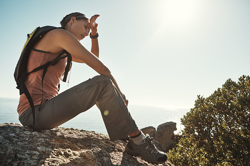 Shot of a young woman taking a break while out on a hike through the mountains