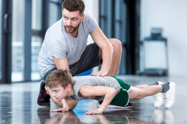istock Boy doing push ups with coach at fitness center 695802444