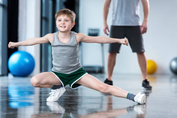 istock Coach controlling boy that doing stretching exercise at fitness center 695803532
