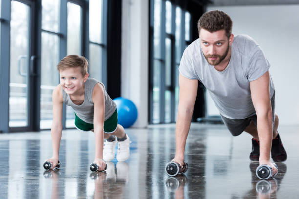 istock Man and boy doing push ups at fitness center 695803838