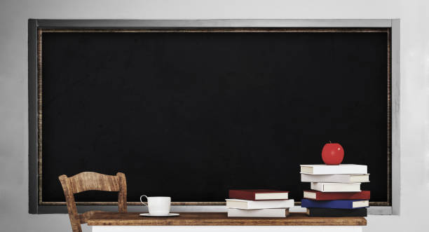 istock Blackboard, table, pile of books and apple, in classroom 695806438