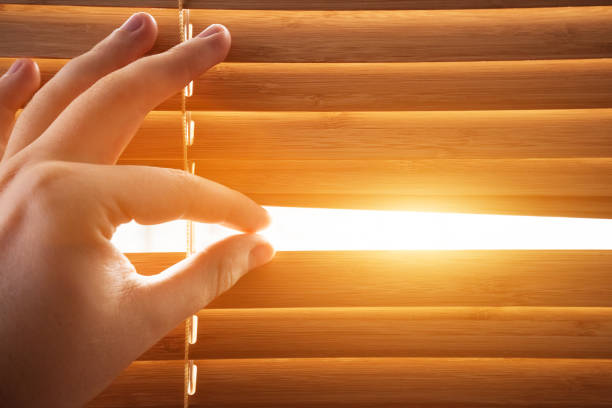 Photo of Looking through window blinds, sun light coming inside.