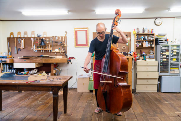 Craftsman testing a double bass in his workshop Craftsman testing a double bass in his workshop contra bassoon stock pictures, royalty-free photos & images