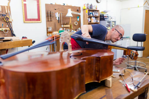 Craftsman tuning a double bass in his workshop Craftsman tuning a double bass in his workshop. Tokyo, Japan. May 2017 contra bassoon stock pictures, royalty-free photos & images
