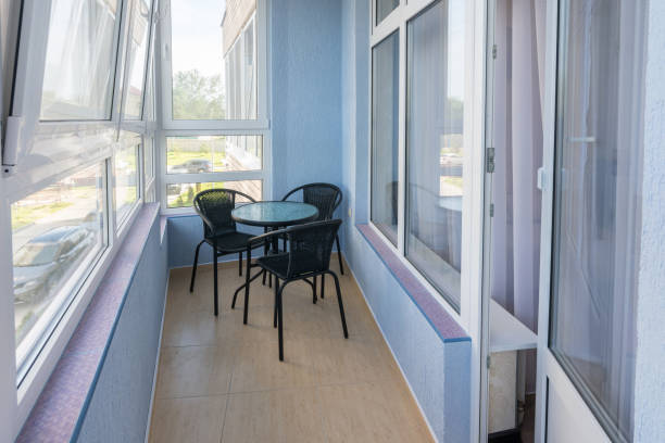 A table and three chairs on the balcony in the apartment of a multistory apartment building stock photo