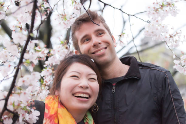 istock International couple enjoying cherry blossoms 695842538