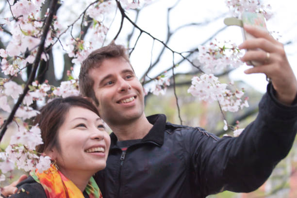 istock International couple enjoying cherry blossoms 695842918