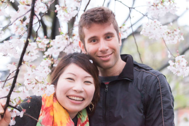 istock International couple enjoying cherry blossoms 695843222
